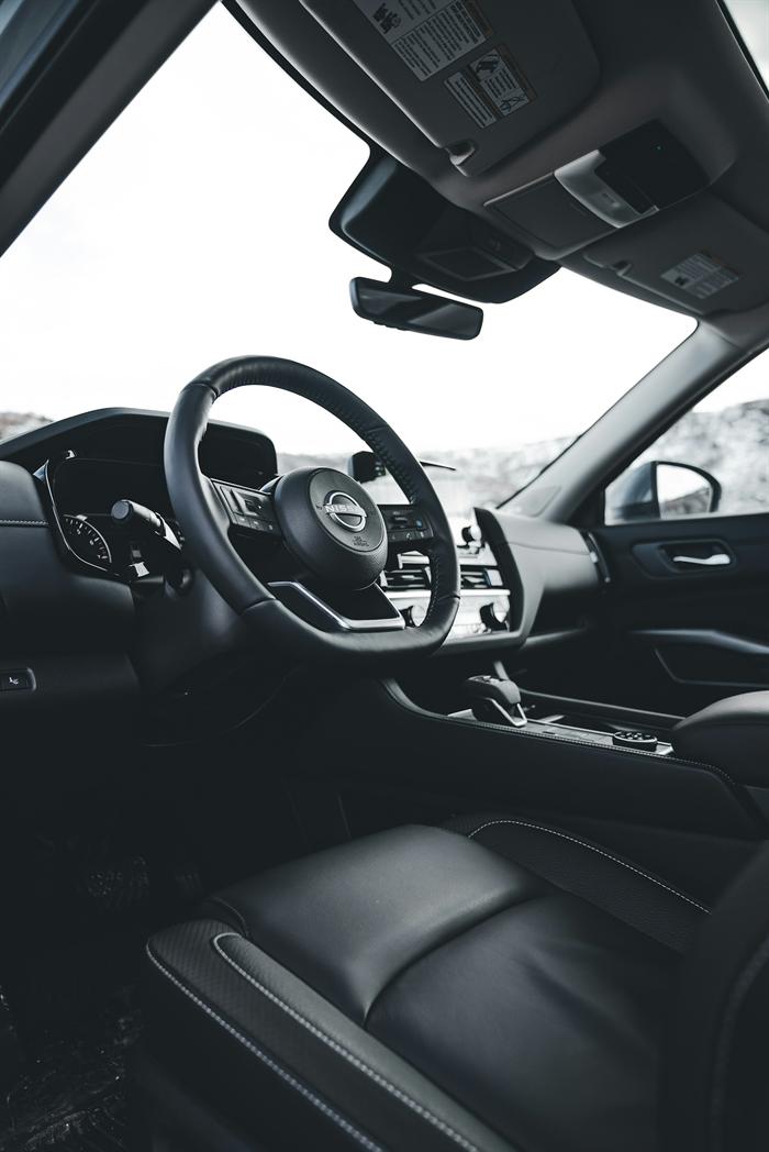 Black leather sports car interior with steering wheel and centre console