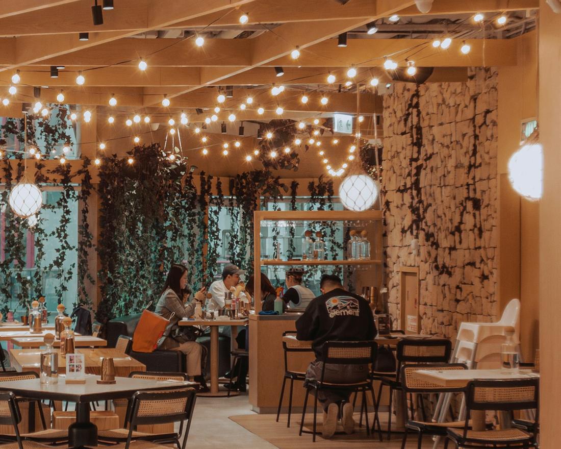 Tables and rattan chairs beneath hanging string lights in the dining room