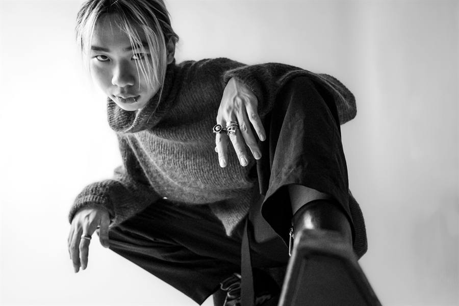 Black and white portrait of a person crouching in a knit jumper