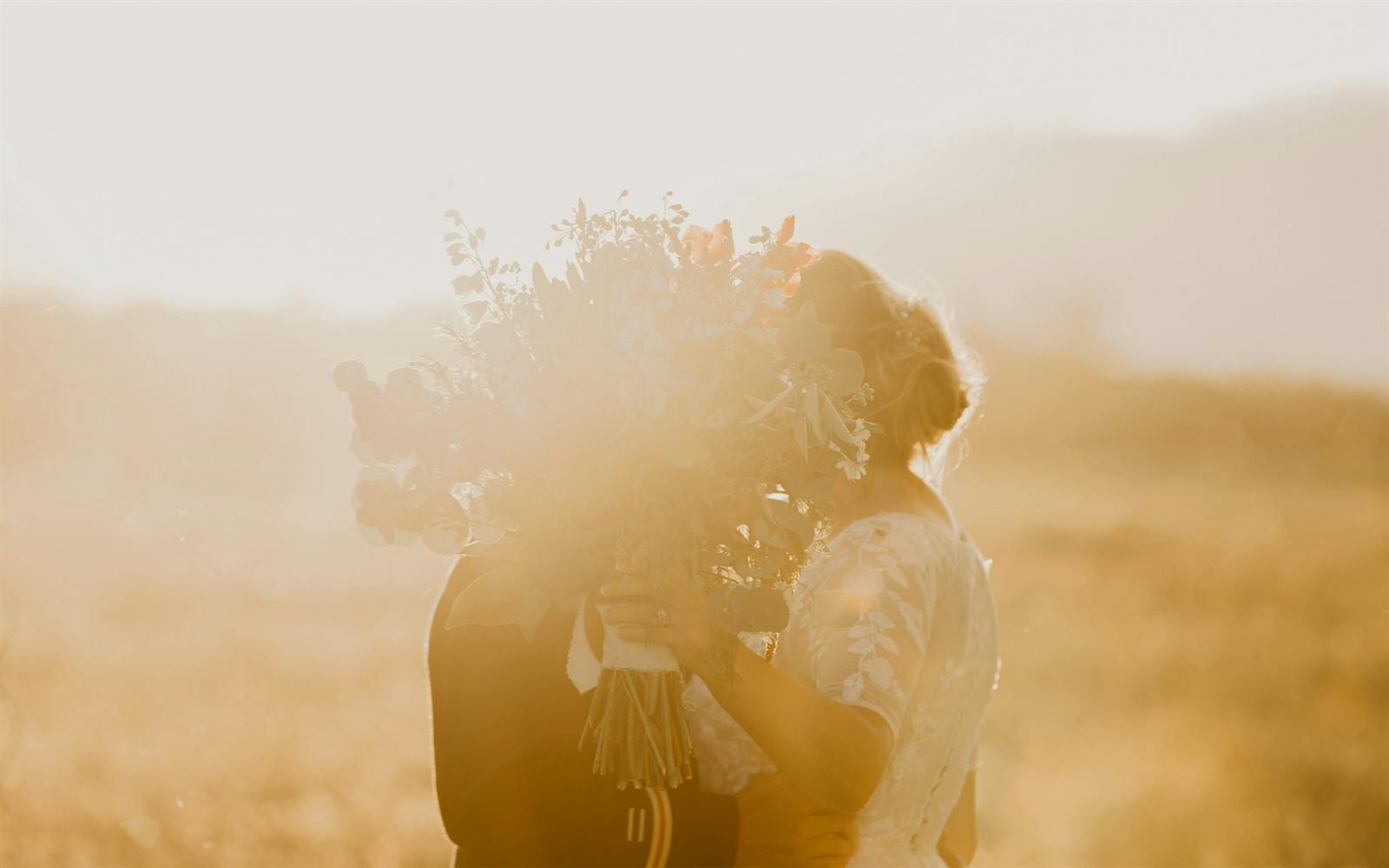 A couple embracing in golden light, a bouquet between them