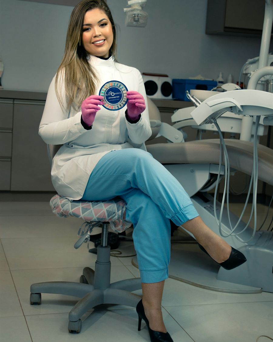 Portrait of Dr Sofia Andrade, seated in a treatment chair in blue scrubs, smiling