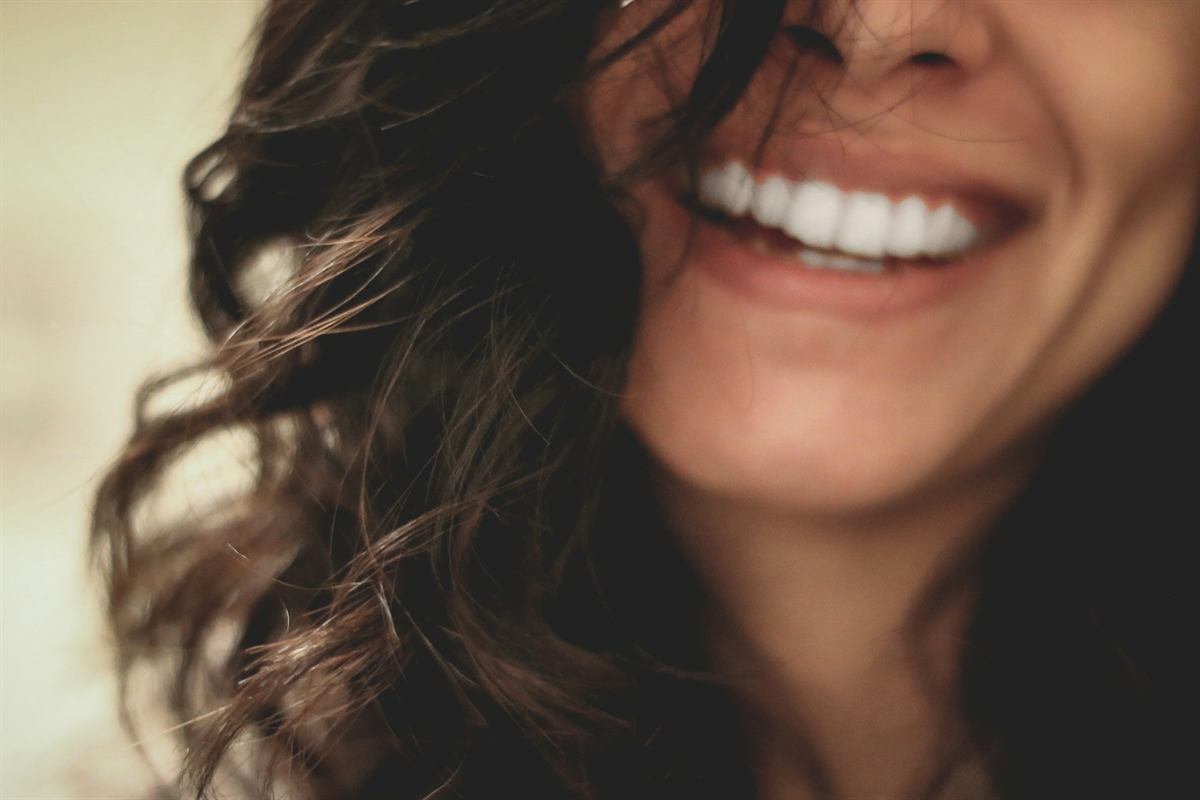 Close-up of a woman&rsquo;s bright smile as she laughs, hair falling across her face