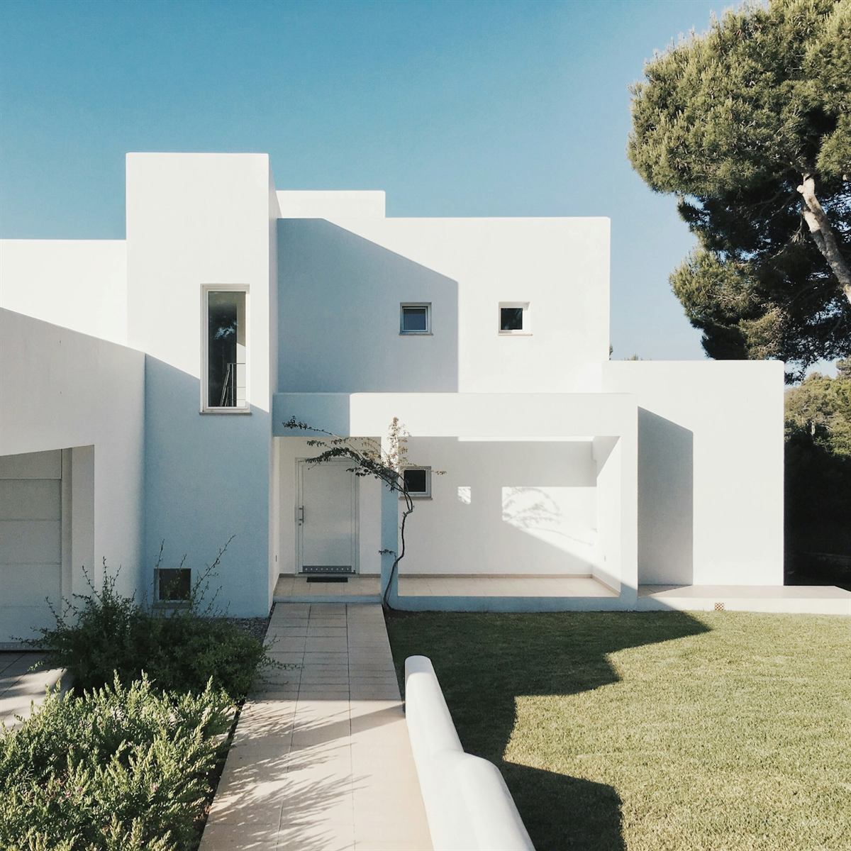Modern Courtyard: a sculptural white house with a covered entrance and lawn