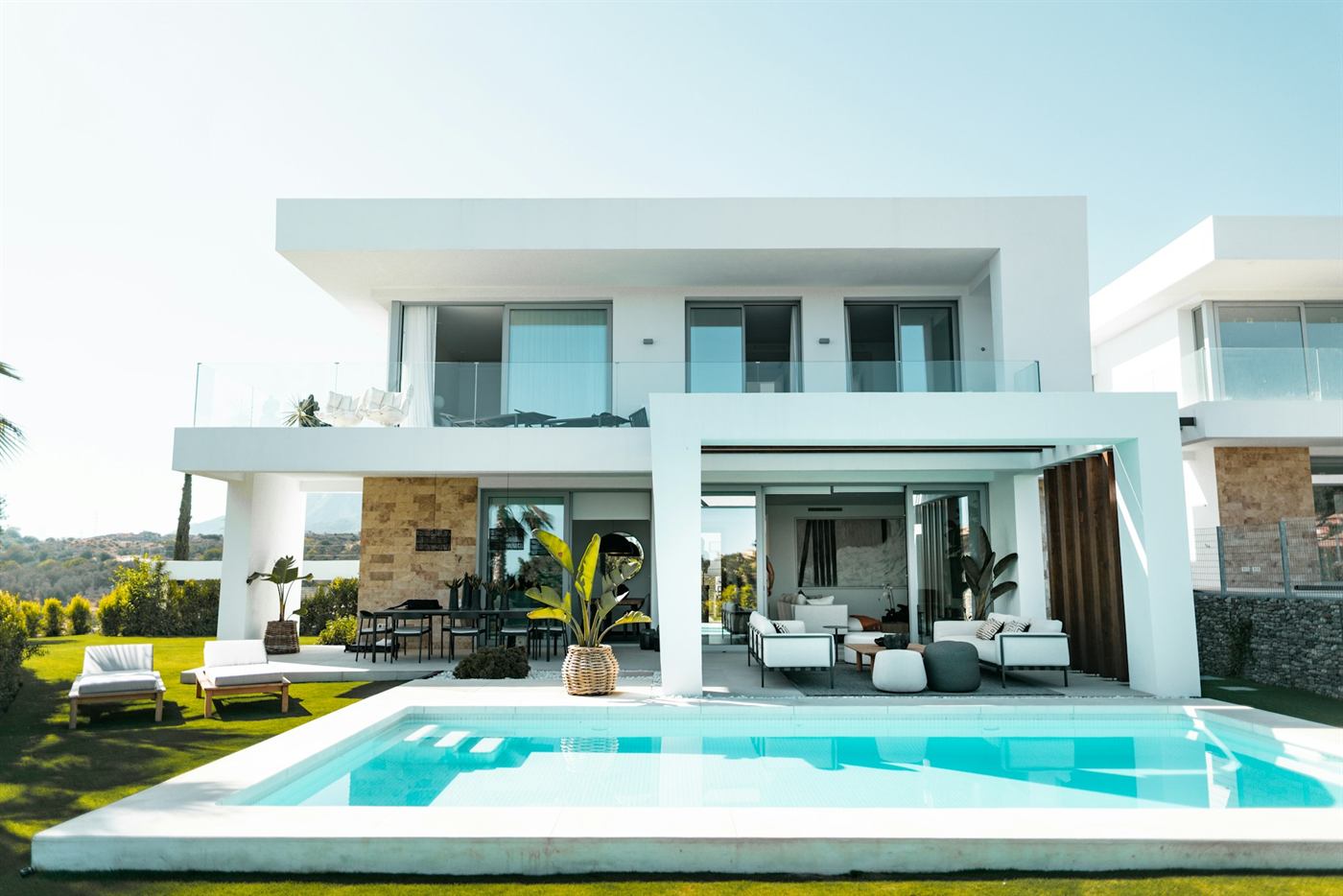 The Cliff House: a white two-storey modern home with glass balustrades, terraces and a turquoise pool above a landscaped garden